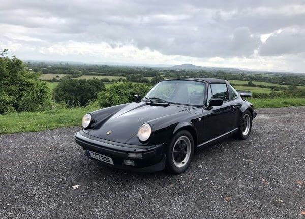 Black Porsche 911 parked in front of countryside - Richard Sharkey customer stories Heritage