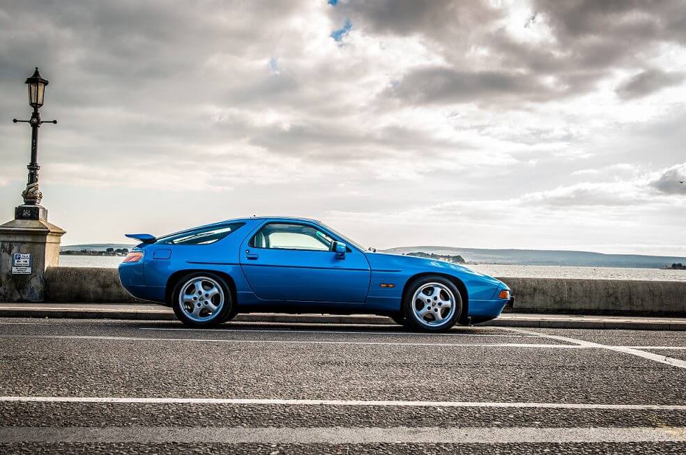 A blue Porsche 928 against a moody sky - top ten most popular classic cars on Instagram